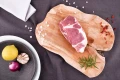 Surowy świeży karczek wieprzowy EKO 500g na drewnianej desce z warzywami i ziołami